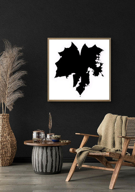 Framed abstract black and white artwork on a dark wall with a wooden chair and decorative items.