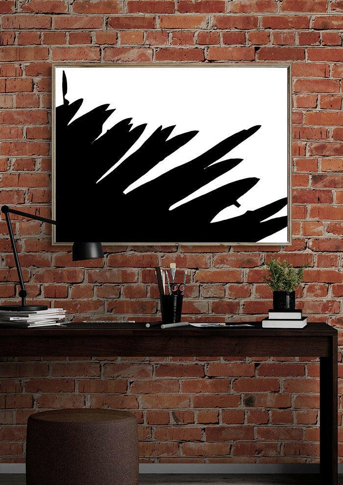 Printable wall art featuring a framed black and white abstract print, on a brick wall above a desk.