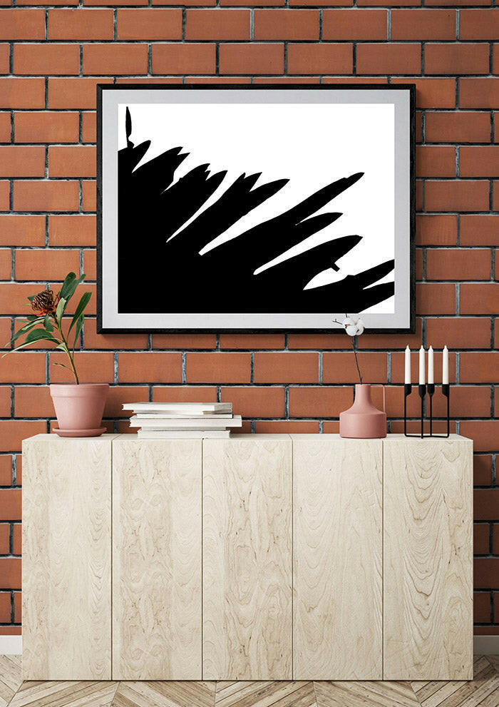 Framed abstract art piece on a brick wall above a wooden cabinet with decorative items.