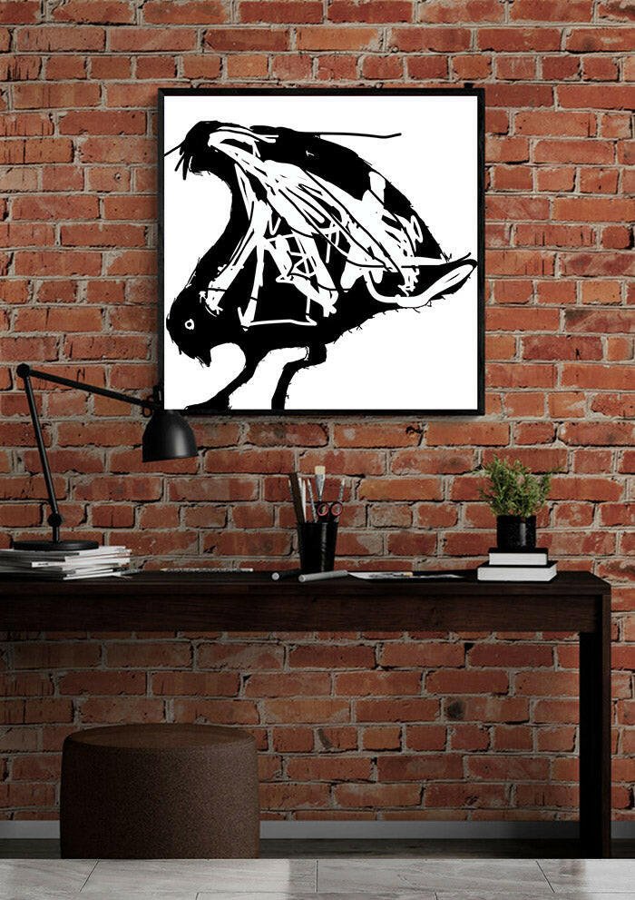 Printable wall art of an abstract seagull in black and white, framed in black and mounted on a brick wall, above a desk.