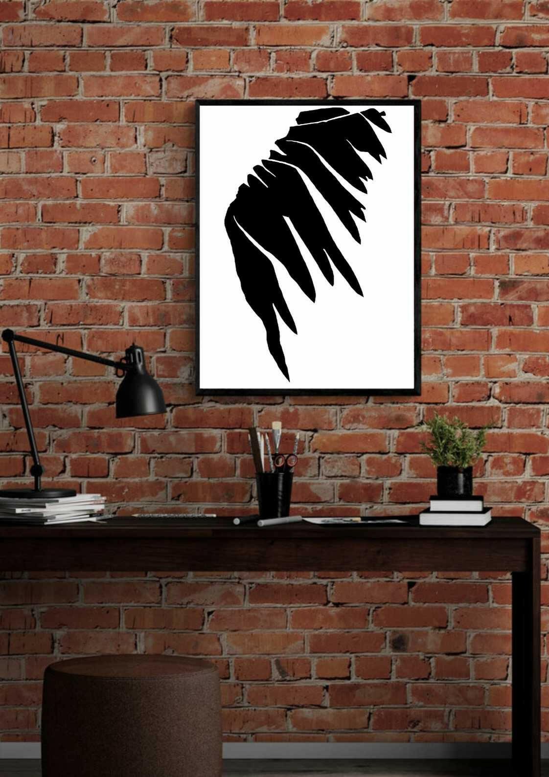Printable wall art of black and white abstract art in a black frame, mounted on a brick wall above a desk.