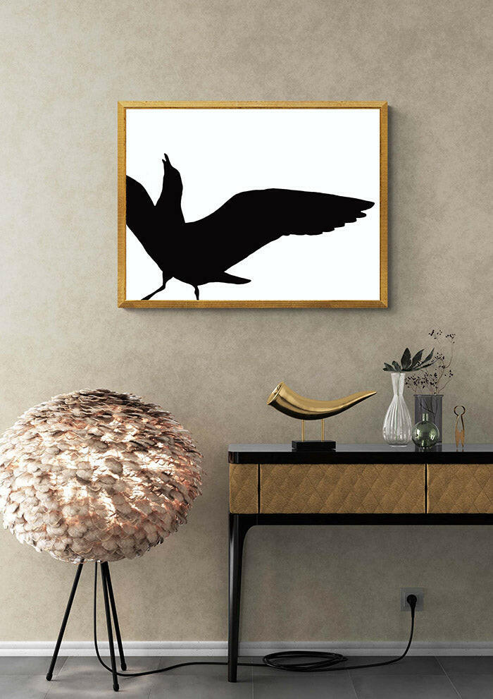 Framed artwork of a black seagull in silhouette on a beige wall with decorative items below.
